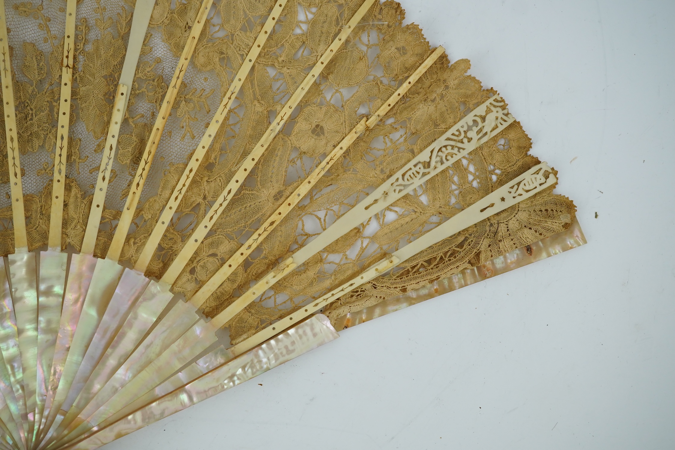 Three novelty fans with a mixed Brussels lace fan and black lace fan, a small language of love in flowers fan, a paper windmill advertising French Café fan, a carved cream Bakelite fan, a black and gilt, lace and sequin